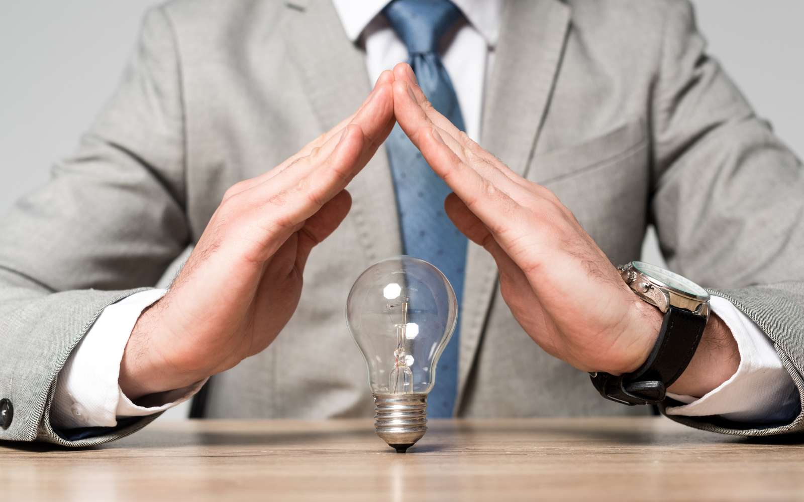Businessman protecting lightbulb representing IP Grants and Support for Canadian Businesses