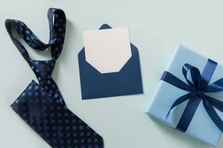 Wrapped gift on desk with tie representing business gift tax Canada
