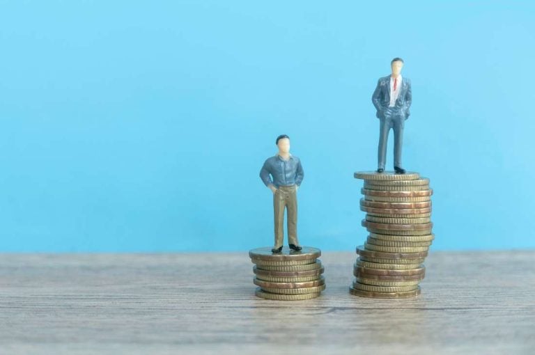 One large pile of coins and one small pile of coins with figures on top representing dividend credit reduction as part of the Ontario small business rate drop